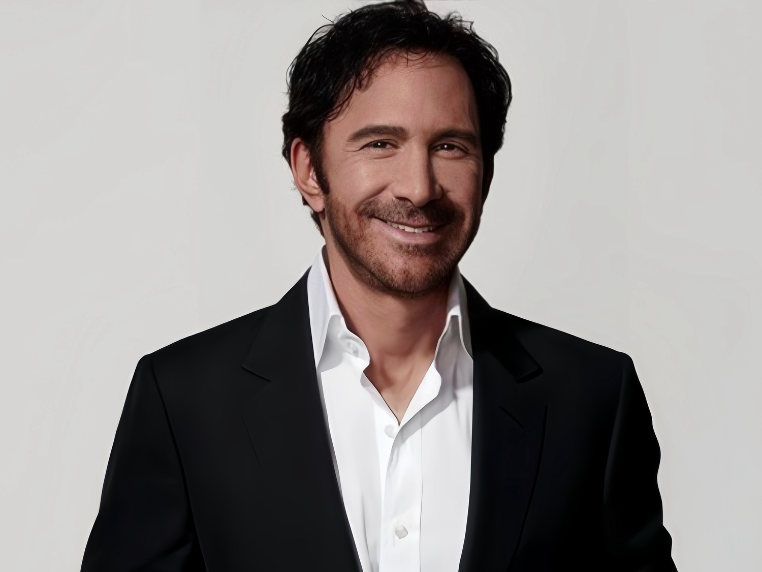 Gray background, Peter Thomas Roth white shirt with black suit, he smiles, very elegant